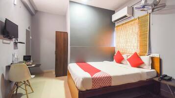 Ein Hotelzimmer mit Bett, Nachttisch, Sessel, Fernseher und Klimaanlage.