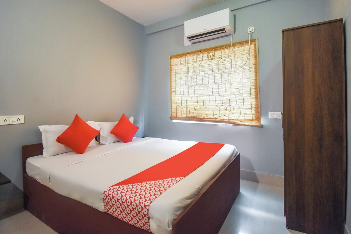 Una habitación de hotel con una cama, un ventanal con persianas, un equipo de aire acondicionado y una puerta de madera.