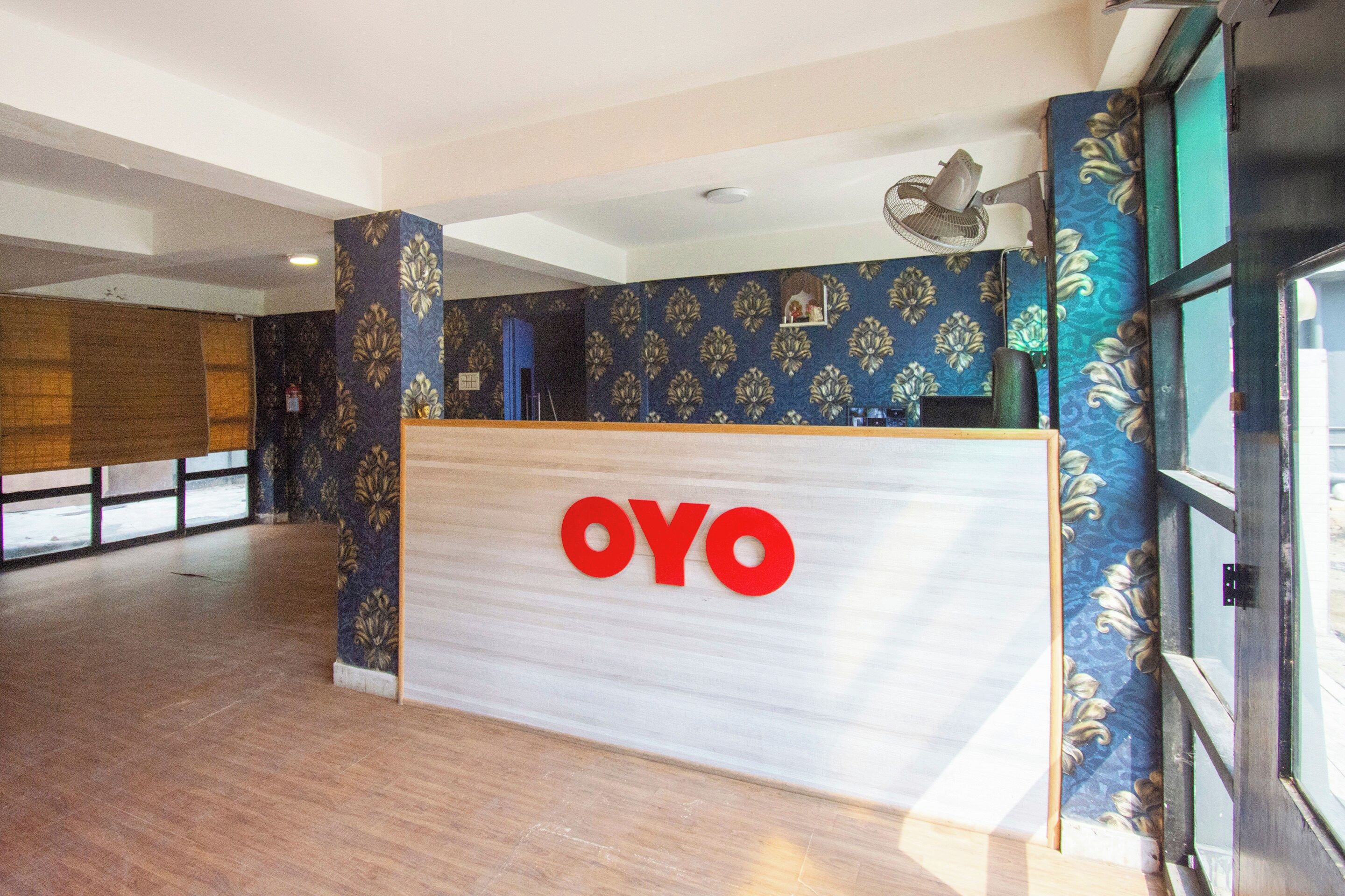 A reception desk with a 'OYO' logo, a patterned wall, and a large window.