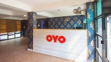 A reception desk with a 'OYO' logo, a patterned wall, and a large window.