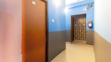 A hallway with a wooden door, a blue wall, and a fire extinguisher mounted on the wall.