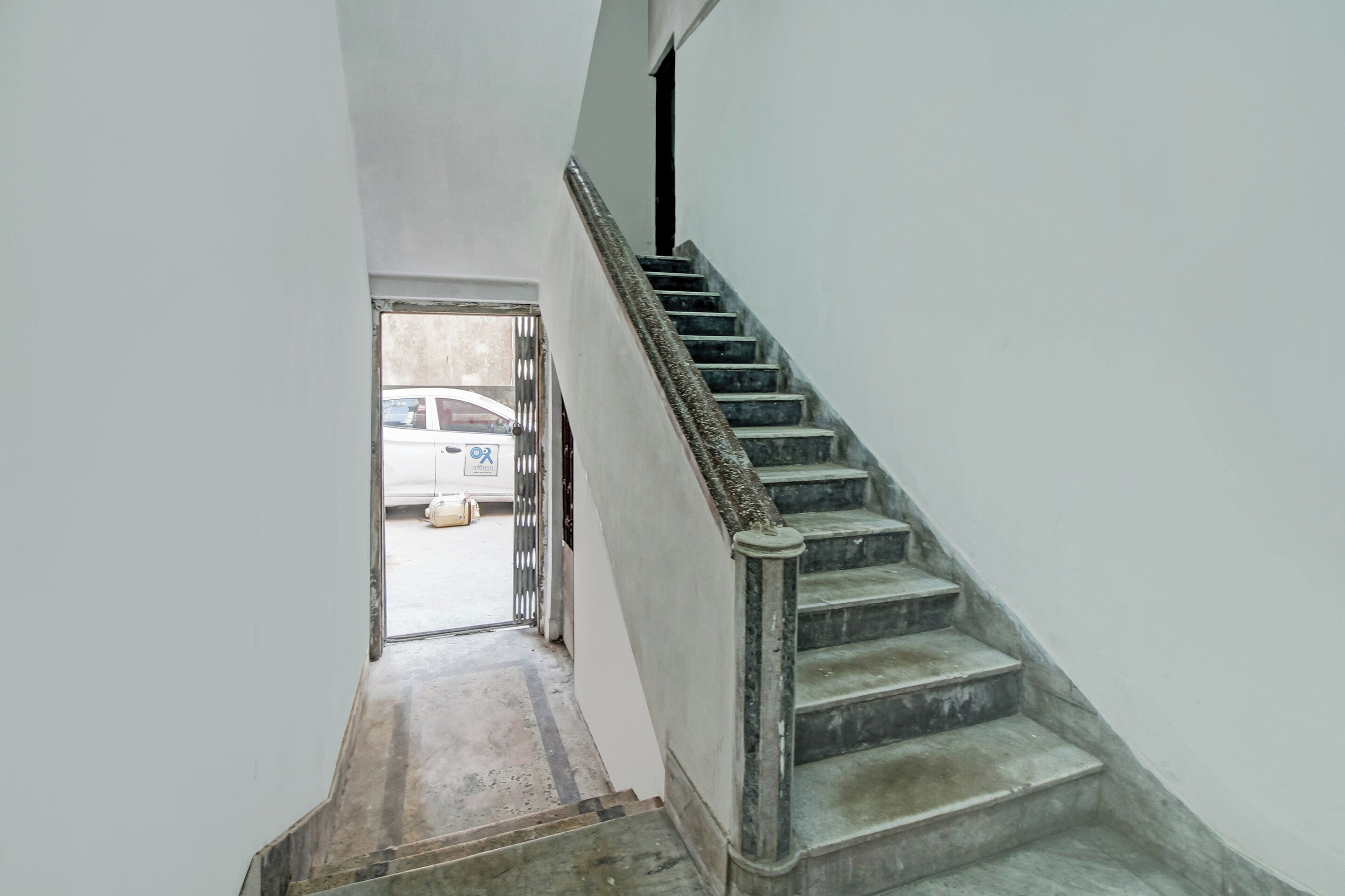 Una escalera con barandilla y una puerta que da a un espacio exterior.