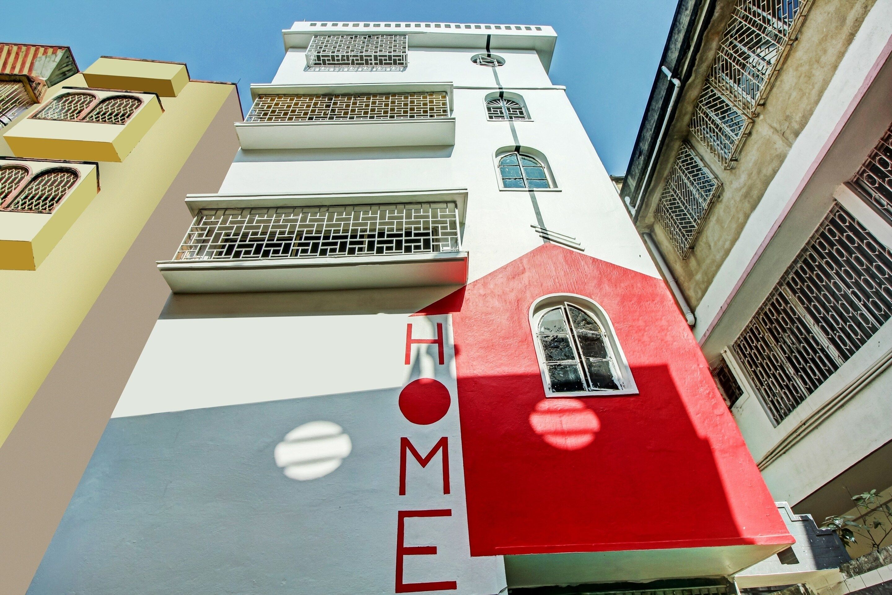 Un edificio con una fachada llamativa de color rojo y blanco, que presenta un gran ventanal y un letrero que dice 'HOME'.