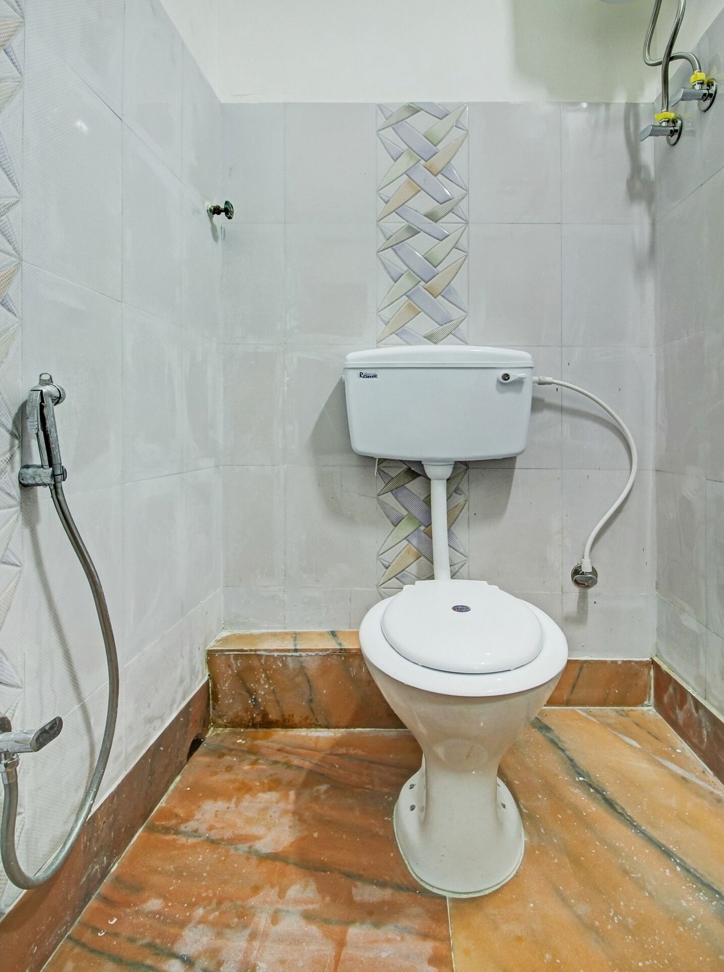 Un baño con inodoro, ducha y pared de azulejos.