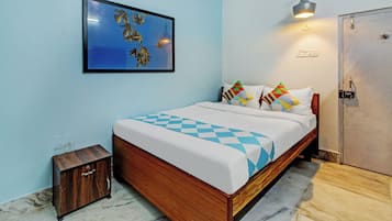 Un dormitorio con cama de madera, una mesita de noche pequeña, un armario, un cuadro en la pared y una lámpara colgante.