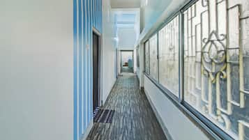 Un pasillo con piso estampado, pared azul a rayas y una reja metálica a la derecha.