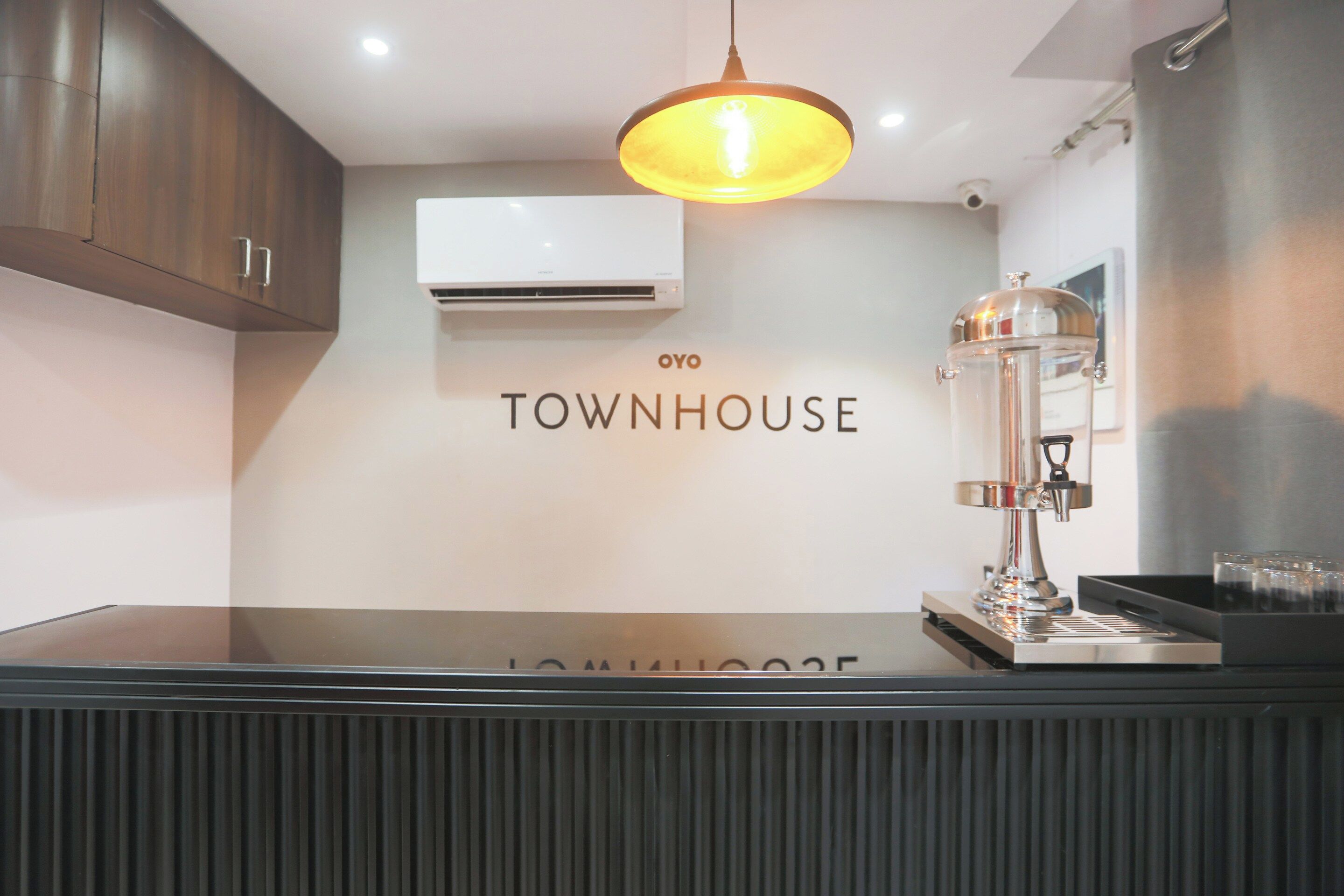 A modern kitchen with a glass countertop, an air conditioning unit, and a coffee machine.