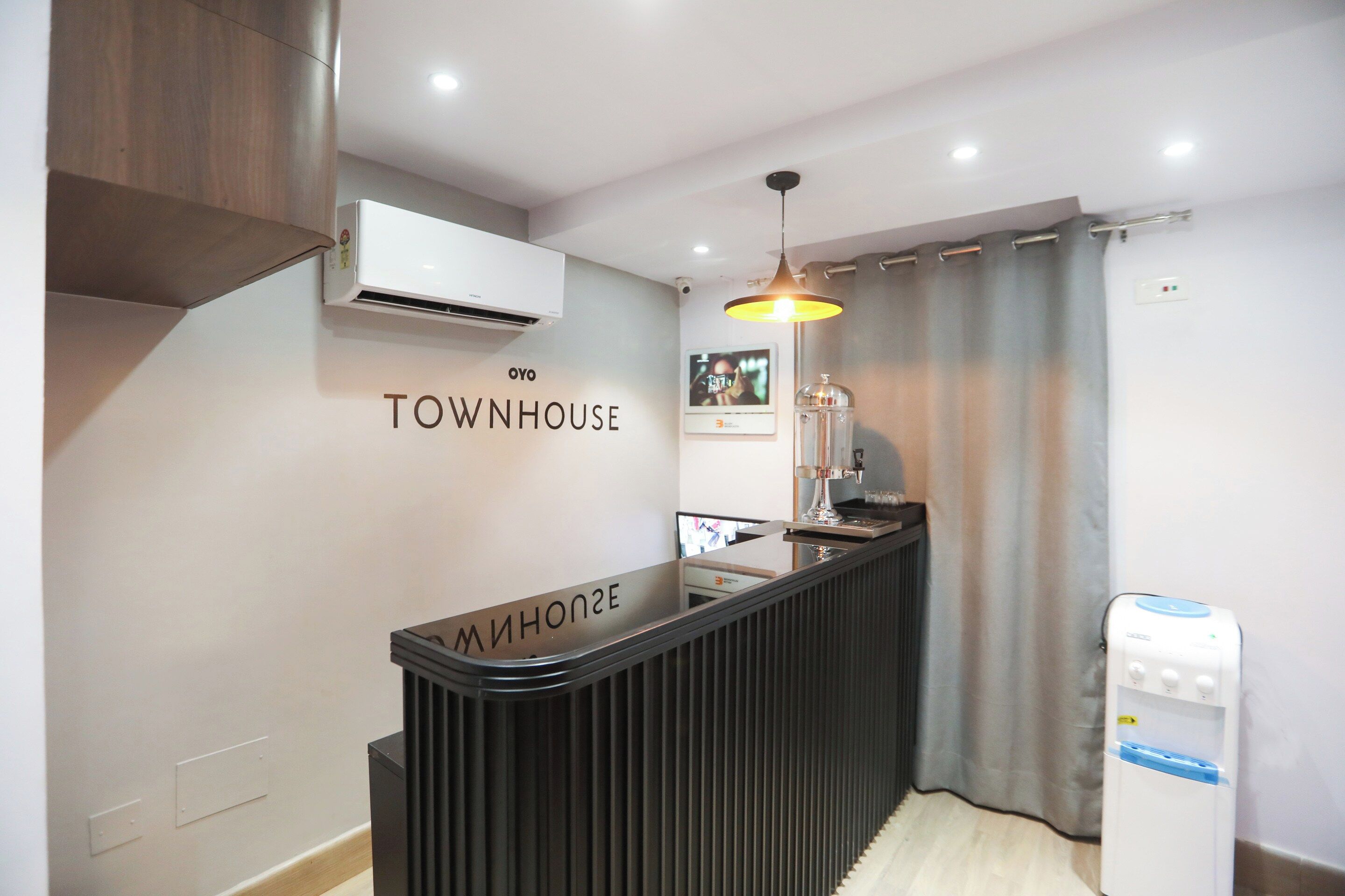 A modern kitchenette with a black countertop, a hanging light fixture, and a water dispenser.