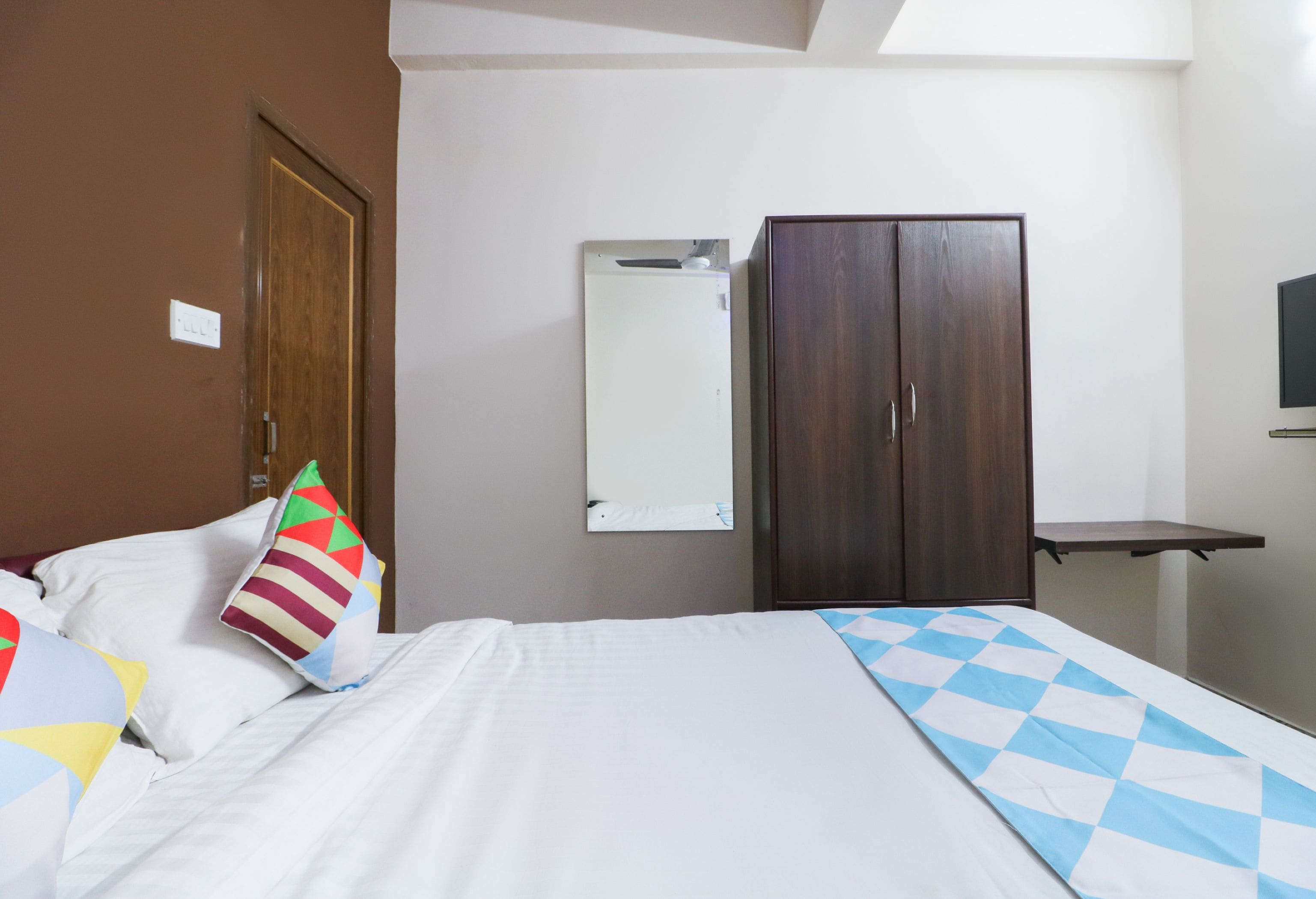 Una habitación de hotel con cama, armario, espejo y televisor.