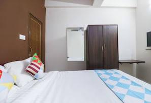 Ett hotellrum med en säng, en garderob, en spegel och en tv.