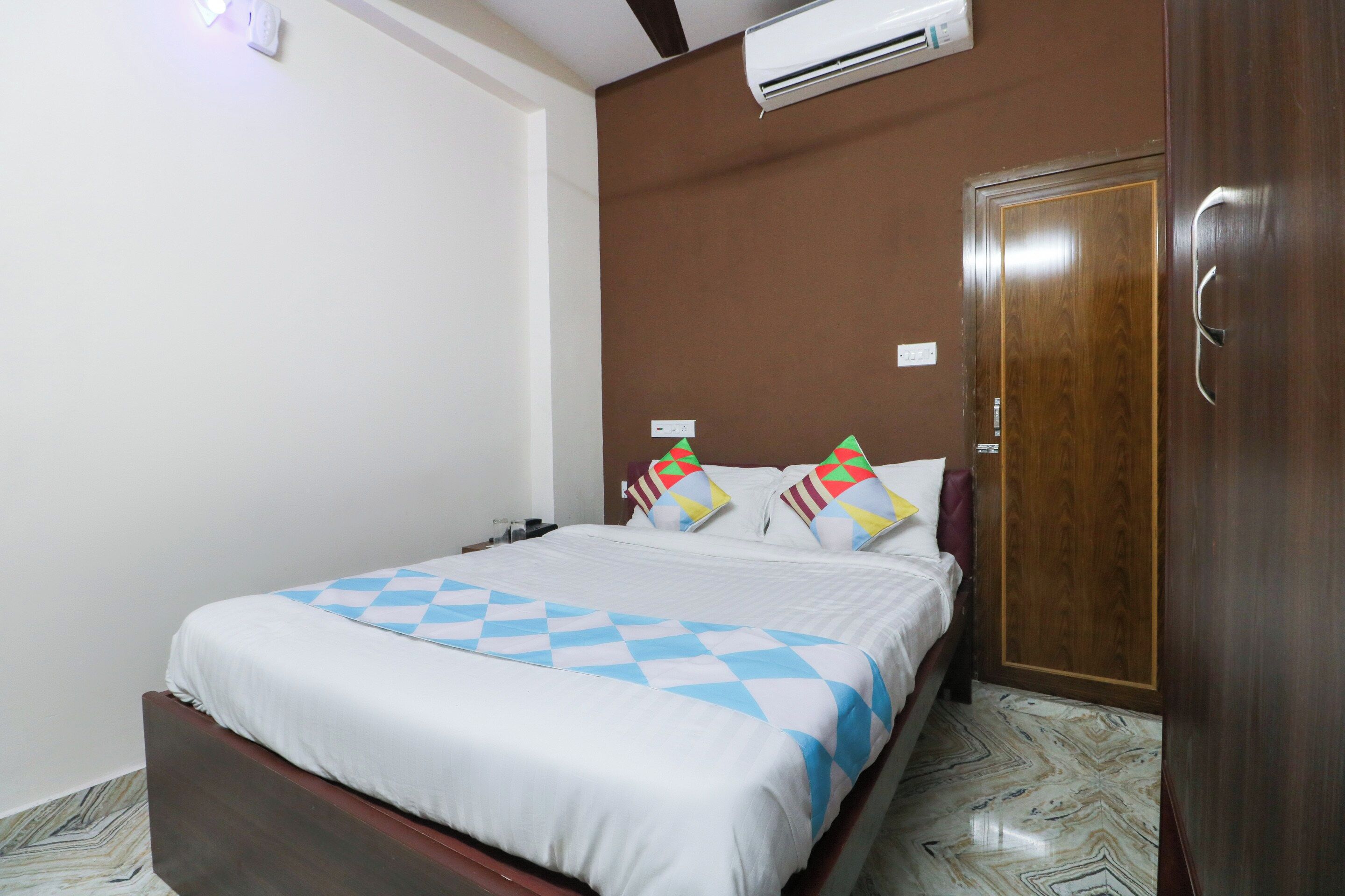 A hotel room with a bed, a wardrobe, and an air conditioning unit.