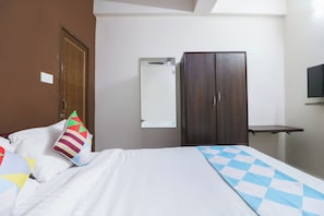 Ett hotellrum med en säng, en garderob, en spegel och en tv.