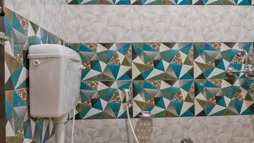 Un baño con inodoro, ducha y pared con baldosas de diseño geométrico.