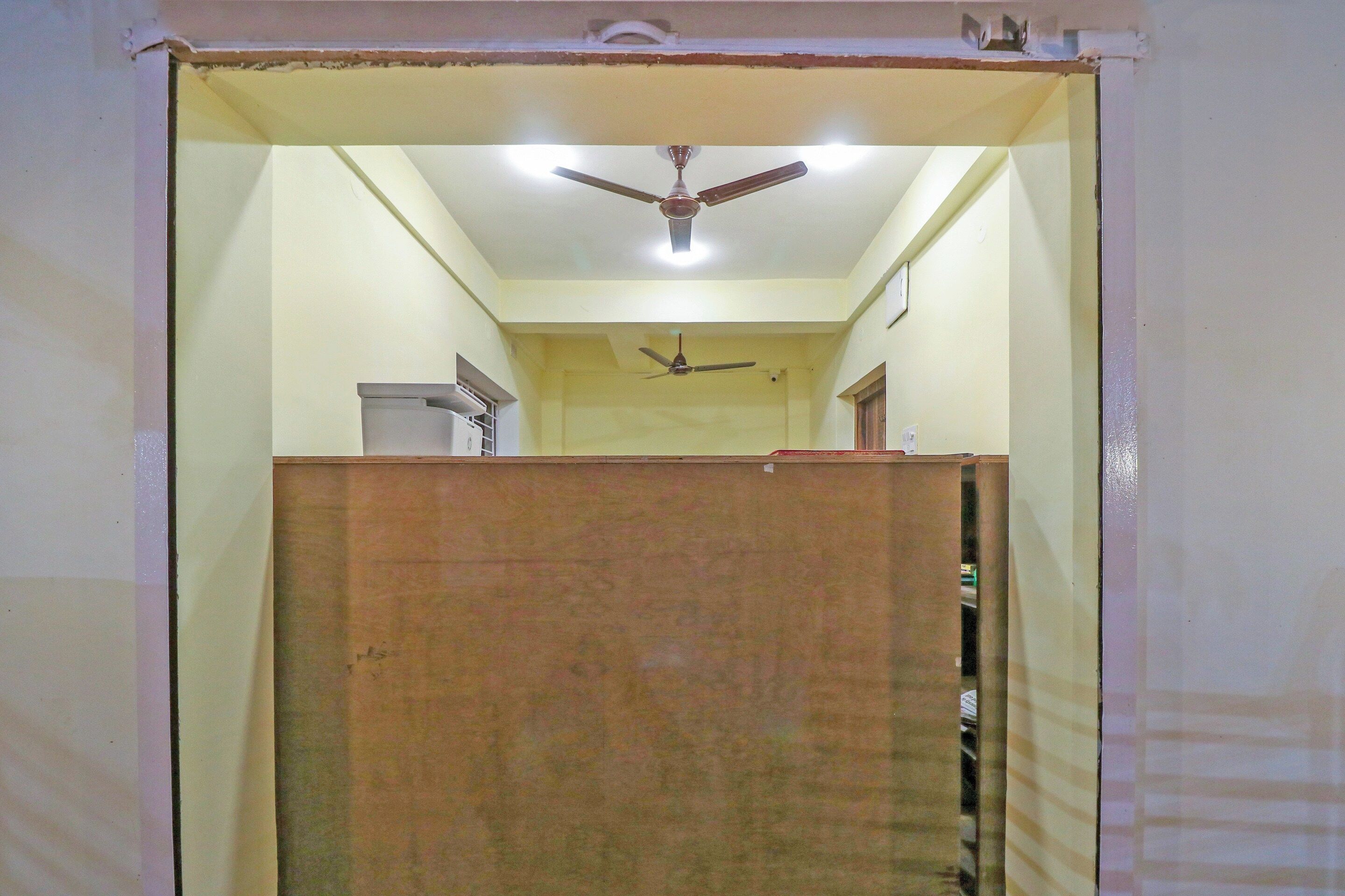 Una habitación con ventilador de techo, separador de madera y una ventana pequeña.