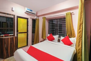 Una habitación de hotel con cama, armario, ventana con cortinas y aire acondicionado.