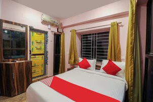 Un dormitorio con cama, ventana con cortinas, espejo y aire acondicionado instalado en la pared.