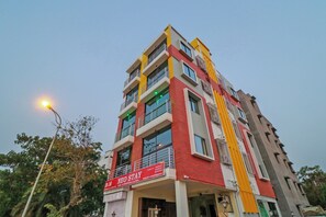 Un edifici de diversos pisos amb façana vermella i groga, balcons i un rètol que diu 'NEO STAY'.