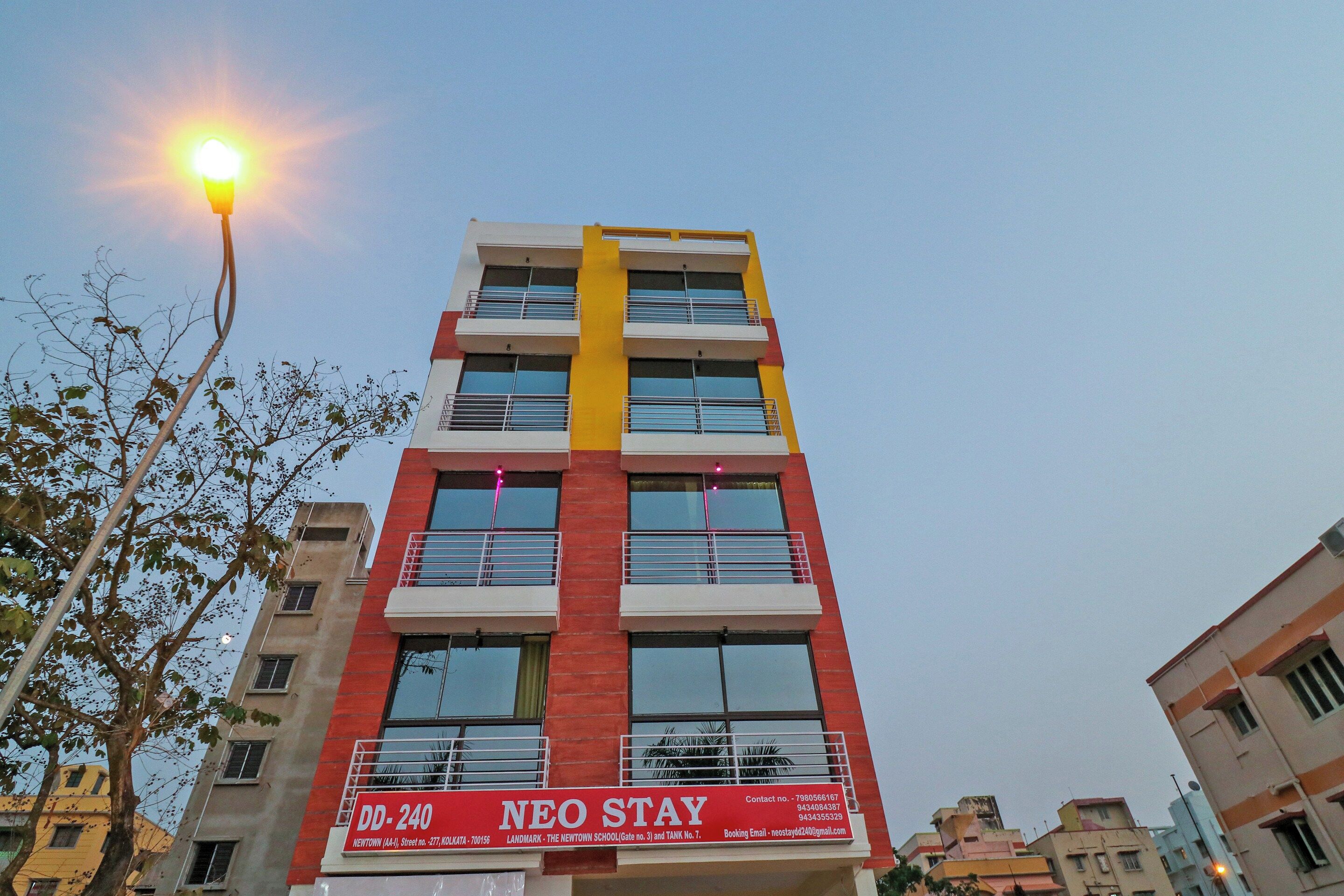 Un edificio de varios pisos con una fachada llamativa roja y amarilla, balcones y un letrero que indica que es una escuela.