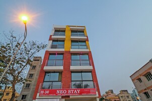 Un edificio de varios pisos con una fachada llamativa roja y amarilla, balcones y un letrero que indica que es una escuela.