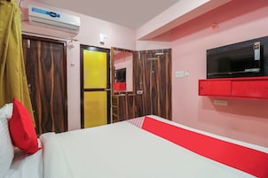 Una habitación de hotel con una cama, televisión, armario y aire acondicionado.