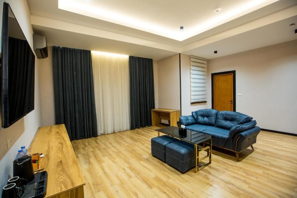 Un salon moderne avec un canapé en cuir, une table basse en verre et une table d’appoint en bois.