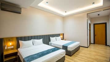Habitación de hotel con dos camas, piso de madera y lámpara en el techo.