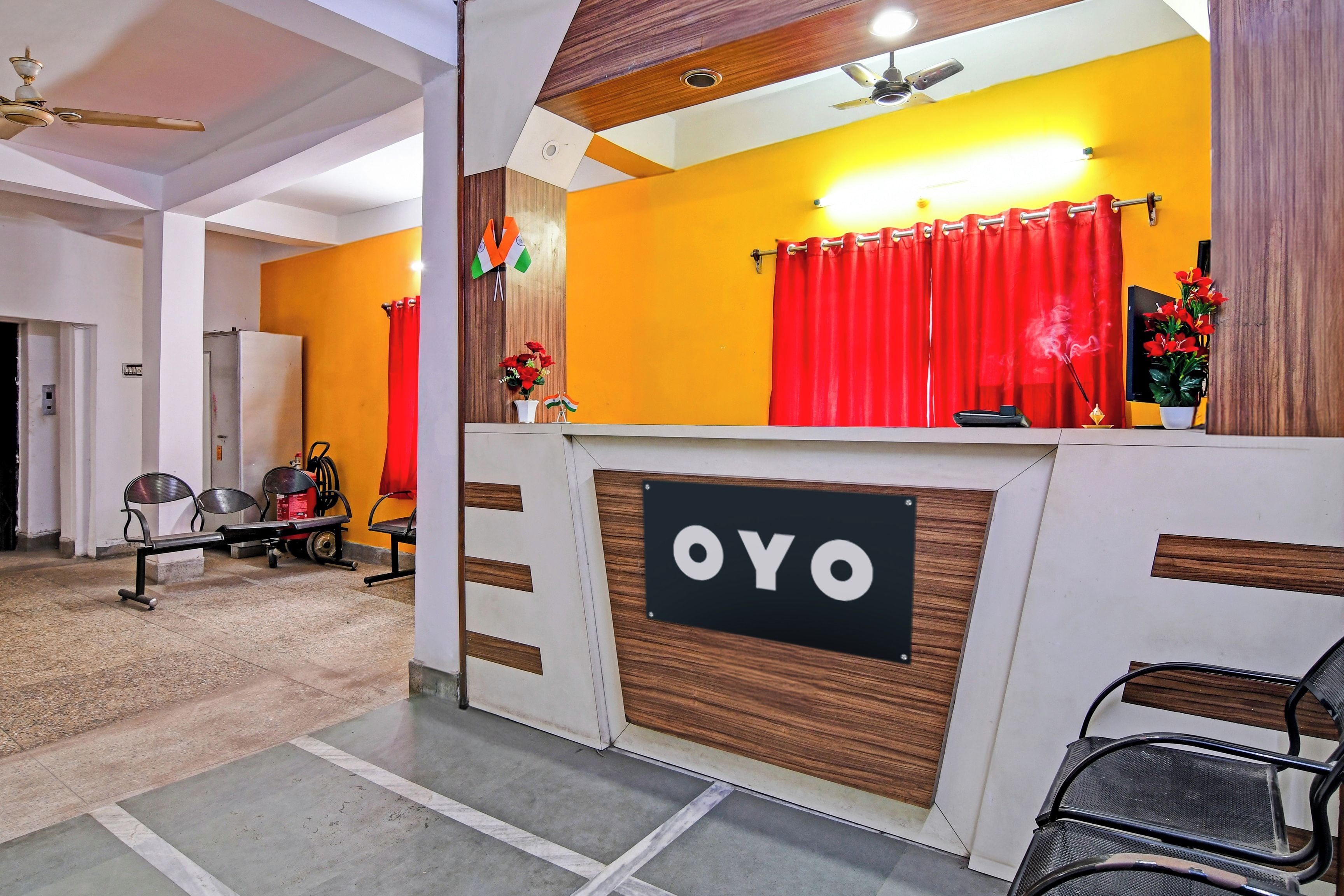 A reception area with a sign reading 'OYO', a red curtain, and a ceiling fan.