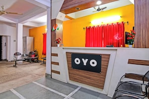 Ett receptionsområde med en skylt med texten ”OYO”, en röd gardin och en takfläkt.