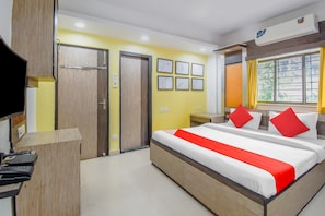 Ett hotellrum med en säng, ett skrivbord, en stol, en tv och ett fönster.