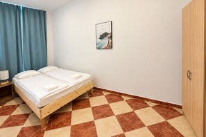 A room with a bed, a nightstand, a wardrobe, and a painting on the wall. - Vienna Beyond Your Door 1BR and Private Lounge (Vienna)