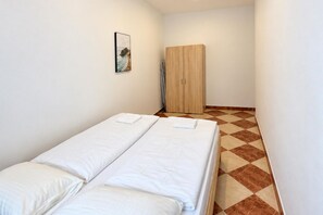 A room with two single beds, a wooden wardrobe, and a checkered floor pattern. - Vienna Beyond Your Door 1BR and Private Lounge (Vienna)
