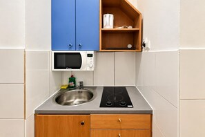 A compact kitchen with a microwave, a sink, and a built-in stove. - Vienna Beyond Your Door 1BR and Private Lounge (Vienna)