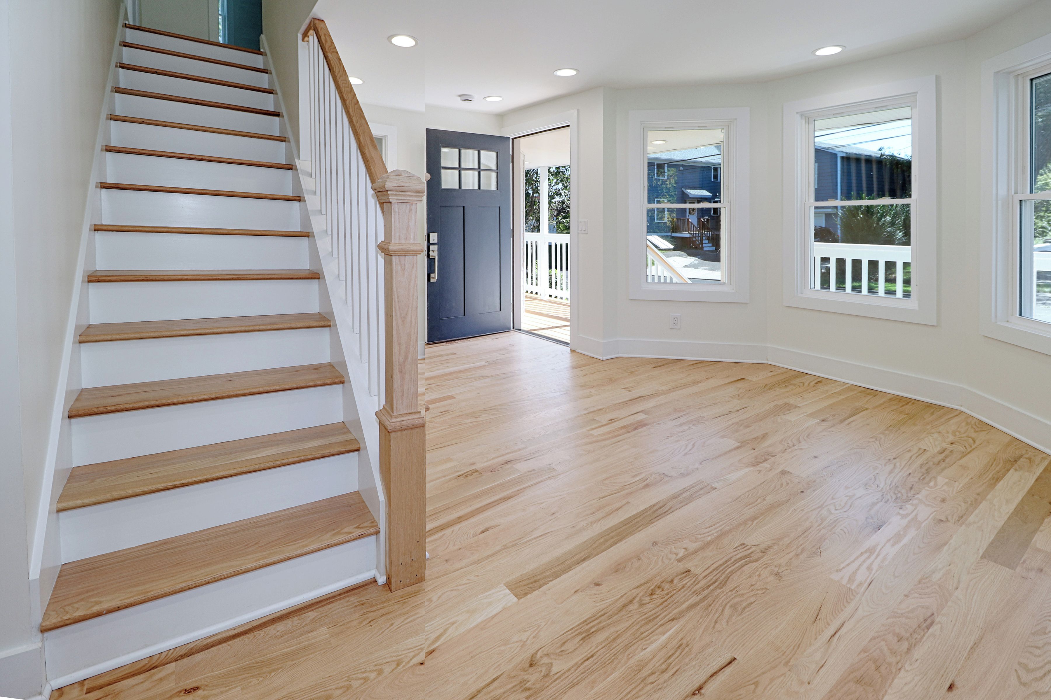 A staircase with wooden steps and a white handrail leading to a dark door.