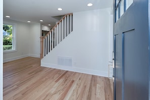 A staircase with wooden handrails and white walls, leading to a landing with a vent. - Fairfield -Charming Completely Renovated 3-bedroom house with AC & 2 car garage. (Fairfield)