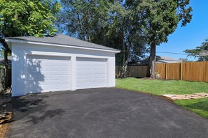 A garage with two doors, a paved driveway, and a wooden fence in the background. - Fairfield -Charming Completely Renovated 3-bedroom house with AC & 2 car garage. (Fairfield)