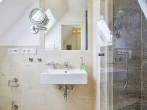 A modern bathroom with a built-in sink, a handheld mirror, a handheld showerhead, and a glass-enclosed shower. - New Love - Suderstr. 18c (Sylt)