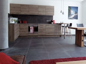 Una cocina moderna con armarios de madera, horno empotrado y comedor con mesa y sillas.