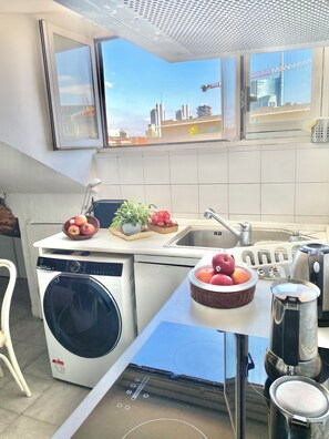 Eine moderne Küche mit Waschmaschine, Spüle und Blick auf die Stadt.