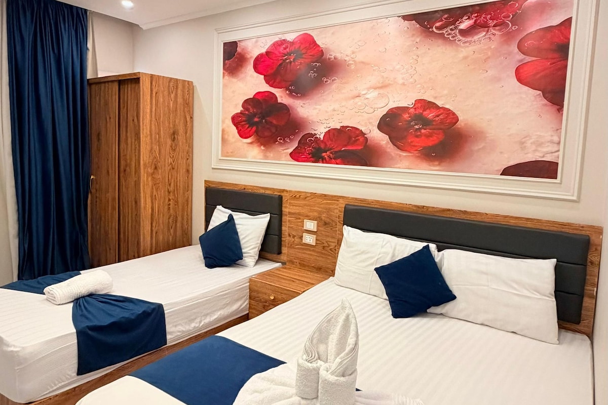 Ein Hotelzimmer mit zwei Betten, einem großen Blumenbild an der Wand und einem Holzschrank.