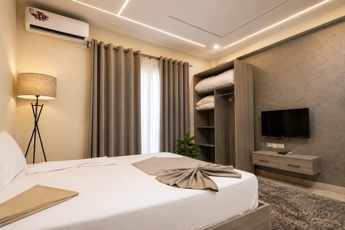 Ein Hotelzimmer mit einem Bett, einem Fernseher, einem Kleiderschrank und einer Klimaanlage.