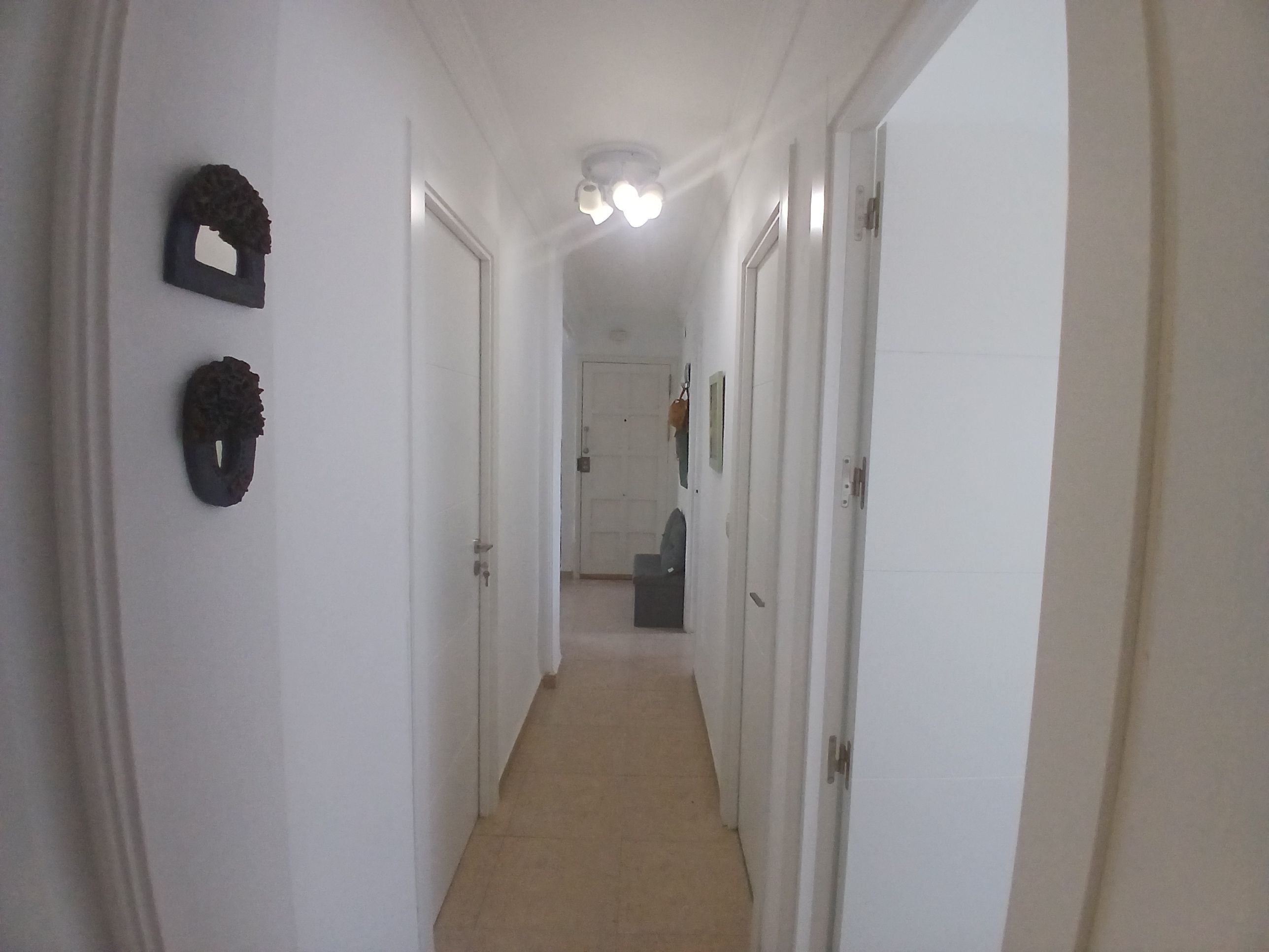 Un couloir étroit aux murs blancs, doté d’un sol recouvert de moquette et de portes donnant sur d’autres pièces.