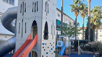 A playground with a slide, climbing wall, and a castle-like structure.
