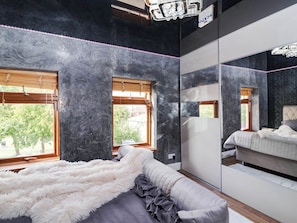 A bedroom with a bed, a large mirror, and a window. - Severnwolf House (Gloucester)