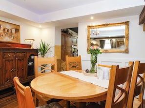 A dining area with a round wooden table, wooden chairs, a vase with flowers, and a mirror with an ornate frame. - Severnwolf House (Gloucester)