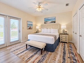 A bedroom with a bed, bedside tables, a bench, a ceiling fan, and a view through the sliding glass door. - Las Flores #B Spacious 2/2 W/Easy Beach Access (South Padre Island)