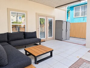 A modern outdoor living area with a sectional sofa, a wooden coffee table, and a grey cabinet. - Las Flores #B Spacious 2/2 W/Easy Beach Access (South Padre Island)