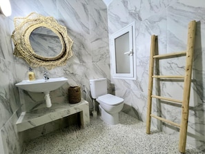 Ein Badezimmer mit Marmorwaschbecken, Toilette und einer Holzleiter.