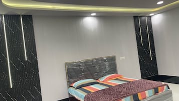 A modern bedroom with a bed, a headboard, and a wall with vertical lines.