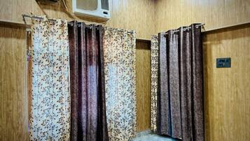 Una habitación con paredes de madera, un ventilador de techo y una zona de ducha con cortinas.
