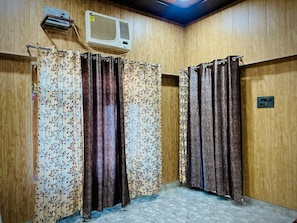 Una habitación con paredes de madera, un ventilador de techo y una zona de ducha con cortinas.